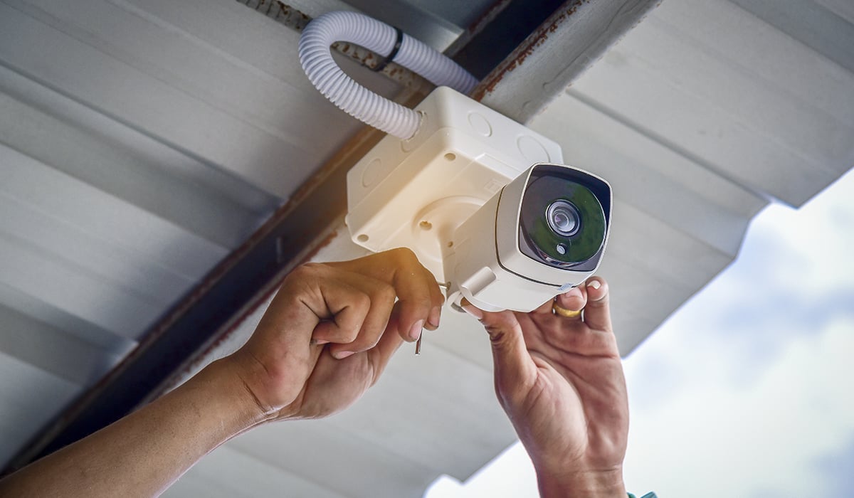 Technician installing CCTV Camera under roof overhang Technician installing CCTV Camera under roof overhang